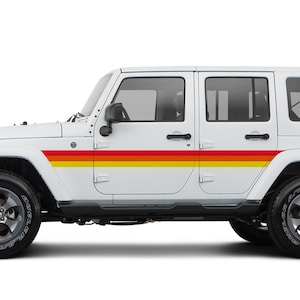 May include: A white four-door SUV featuring a horizontal side decal with three distinct stripes in red, orange, and yellow. The vehicle has black door handles, black side mirrors, dark gray alloy wheels with black tires, and a spare tire mounted on the rear.