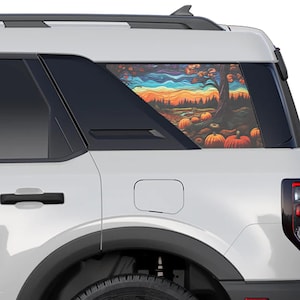 May include: A white SUV with a rear window decal featuring a colorful autumn scene with a tree, pumpkins, and a blue sky.