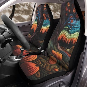 May include: Car seat covers featuring a colorful autumn design. The covers display a vibrant illustration of a tree with pumpkins, leaves, and a rainbow-colored sky. The seats are black with a detailed, artistic print.