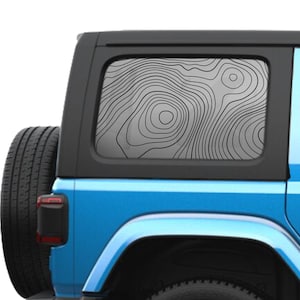 May include: A light grey window decal featuring a black topographic map pattern with concentric contour lines applied to the rear side window of a bright blue vehicle with a black spare tyre mounted on the back.