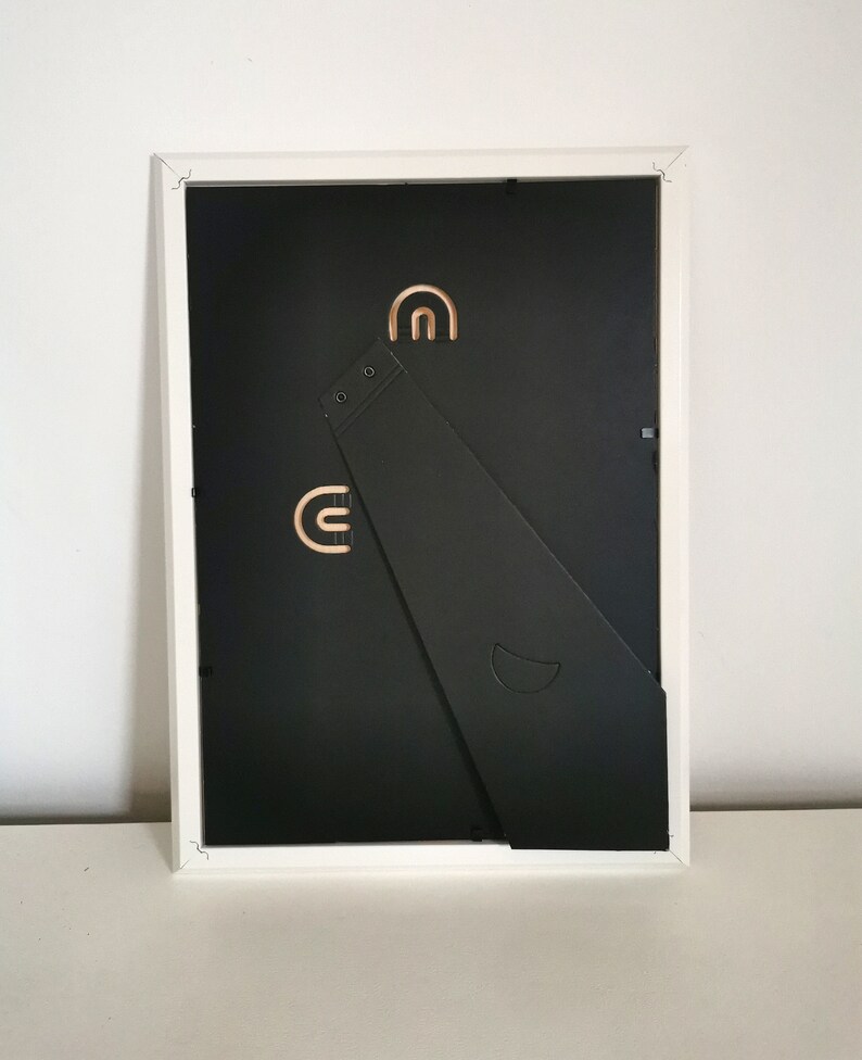 May include: White picture frame with a black backing and a fold-out easel stand. The easel stand has two slots for hanging the frame on a wall.