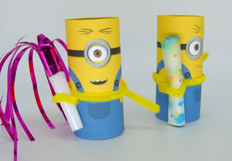May include: Two yellow and blue Minion-themed cardboard tubes decorated with googly eyes, black lines, and a yellow pipe cleaner. One Minion holds a pink and white party blower with a streamer, and the other holds a blue and white rolled-up paper.