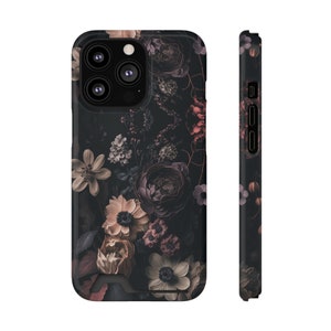 May include: A black phone case with a floral design. The flowers are in shades of pink, purple, and white, and they are arranged on a dark background. The case has a cutout for the camera lens.