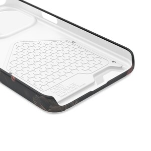 May include: Close-up of the inside of a black and white phone case with a card storage compartment. The compartment has a honeycomb pattern and the text "CARD STORAGE Made in South Korea" is printed on the bottom.