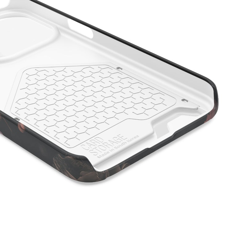 May include: Close-up of the inside of a black and white phone case with a card storage compartment. The compartment has a honeycomb pattern and the text "CARD STORAGE Made in South Korea" is printed on the bottom.
