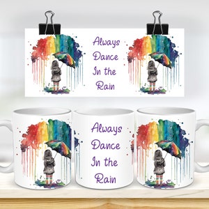 May include: White ceramic mug with a colorful watercolor rainbow design. The design features a girl holding an umbrella standing under the rainbow. The text "Always Dance In the Rain" is printed on the mug.