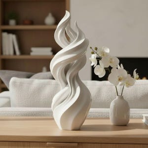 May include: A white, abstract sculpture with a swirling, flame-like design. The sculpture is placed on a wooden table, next to a small white vase with white orchids. The background includes a sofa, bookshelf, and fireplace.