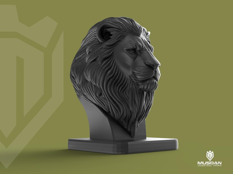 May include: A black lion head sculpture with a detailed mane and facial features. The sculpture is mounted on a rectangular base. The background is a muted olive green. The sculpture is a decorative item.
