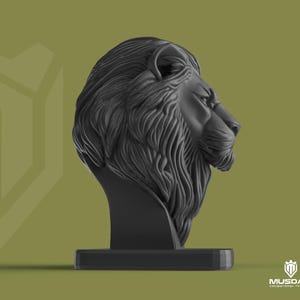 May include: A black lion head sculpture with detailed mane and facial features, mounted on a rectangular base. The background is a muted olive green. The sculpture is a decorative item.