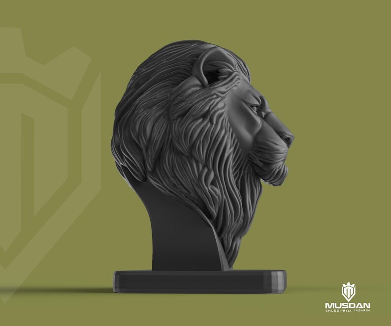 May include: A black lion head sculpture with detailed mane and facial features, mounted on a rectangular base. The background is a muted olive green. The sculpture is a decorative item.