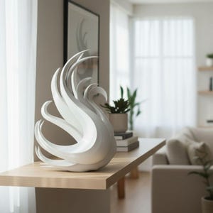 Può includere: Una scultura di cigno bianco con collo curvo e dettagli alari fluenti. Il pezzo decorativo è posto su una mensola in legno chiaro in una stanza ben illuminata. Il cigno è un elemento di arredo moderno.