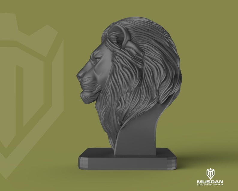 May include: A dark grey lion head sculpture, depicting the animal's profile. The sculpture is mounted on a rectangular base. The lion's mane is detailed, and the design is modern and artistic.