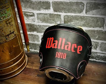 May include: A black leather cover featuring red stitching and the red text Wallace 1810 embossed on the front. The cover is shaped to fit over a circular object and includes black lacing details along the sides, providing a structured appearance.