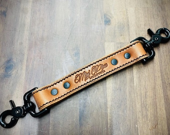 Puede incluir: Una correa de cuero marrón con costuras negras y cierres metálicos. La correa está estampada con el texto "Old Brown Leatherworks".