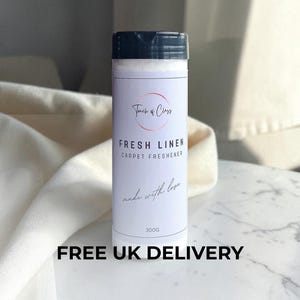 May include: A cylindrical white plastic bottle of carpet freshener with a black flip-top cap. The label features a circular logo with the text Touch of Class, followed by FRESH LINEN CARPET FRESHENER, made with love, and the weight 300g.