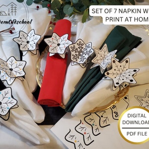 May include: Set of seven printable napkin wraps featuring a snowflake design. The wraps are printed on white paper and have black outlines with colorful accents. The text "SET OF 7 NAPKIN WRAPS PRINT AT HOME" is visible at the top of the image. The text "DIGITAL DOWNLOAD PDF FILE" is visible at the bottom of the image.
