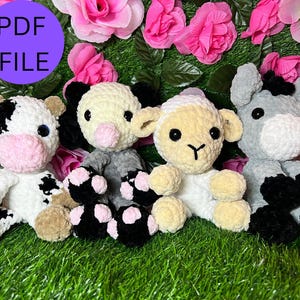 May include: Four crocheted stuffed animals: a cow, a pig, a lamb, and a donkey. The animals are all sitting on a bed of green grass. The cow is black and white, the pig is pink and white, the lamb is white, and the donkey is gray.