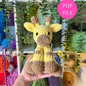 May include: A handmade, plush giraffe toy in yellow and brown. The giraffe has a soft, textured appearance with detailed features. The image includes a pink circle with the text "PDF FILE".