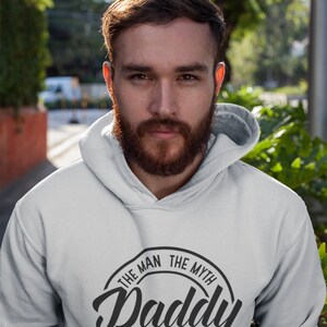 May include: A gray hooded sweatshirt with a black circle graphic that says "The Man The Myth Daddy The Legend".