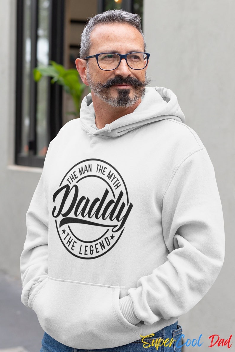May include: White hooded sweatshirt with a black circle graphic that says "The Man The Myth Daddy The Legend".
