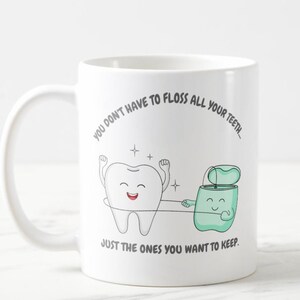 May include: White ceramic coffee mug with a cartoon tooth and a cartoon floss container. The text on the mug reads "You don't have to floss all your teeth... Just the ones you want to keep."