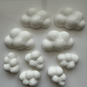 Puede incluir: Diez formas de nubes de espuma blanca de diferentes tamaños. Las nubes están hechas de una espuma suave y texturizada y tienen una forma ligeramente redondeada.