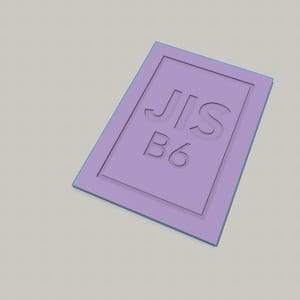 Könnte beinhalten: Ein rechteckiges, hellviolettes flaches Objekt mit einem erhabenen Rahmen. In der Mitte des Objekts befindet sich der eingeprägte, vertiefte Text 'JIS B6' in einer klaren serifenlosen Schrift. Der Artikel hat eine glatte, matte Oberfläche.