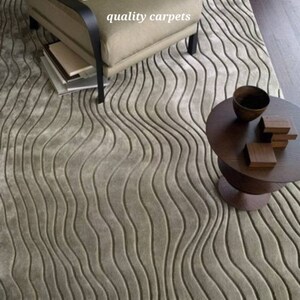 May include: A light gray area rug with a wavy, textured pattern. The rug is in a living room setting with a chair and a side table.