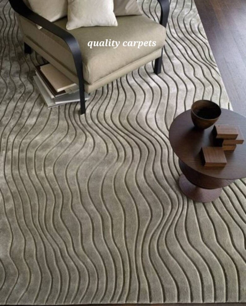 May include: A light gray area rug with a wavy, textured pattern. The rug is in a living room setting with a chair and a side table.