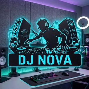 May include: A neon-style wall sign featuring a silhouette of a DJ wearing headphones, positioned between two large speakers and a mixing console. The text DJ NOVA is displayed in bold, glowing cyan letters at the bottom of the rectangular graphic.