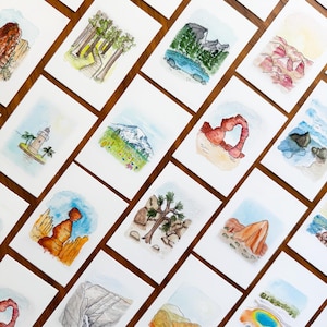 May include: A collection of watercolor art cards featuring various landscapes and landmarks. The cards showcase scenes of mountains, deserts, and forests, with a focus on natural formations and architectural structures. The artwork is rendered in soft, natural colors.