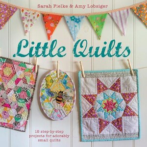 May include: The book cover for "Little Quilts" shows small, colourful quilts suspended on a line, with the authors' names, Sarah Fielke & Amy Lobsiger, displayed above. The text reads "15 step-by-step projects for adorably small quilts".