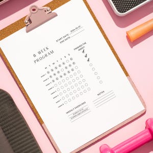 Może przedstawiać: Biała 8-tygodniowa lista kontrolna programu na klipsie z brązowym korkowym podkładem. Lista kontrolna zawiera kalendarz z dniami tygodnia i polami wyboru dla każdego dnia. Lista kontrolna zawiera również sekcję na cotygodniowe ćwiczenia i notatki.