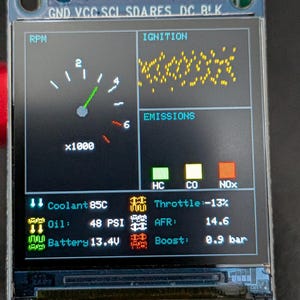 Può includere: Un modulo display digitale rettangolare etichettato M130T-240240-RGB-7-V1.1. Lo schermo mostra un'interfaccia cruscotto con contagiri, stato dell'accensione e livelli di emissioni. Il testo include Coolant 85C, Oil 48 PSI, Throttle -13%, AFR 14.6, Battery 13.4V e Boost 0.9 bar.