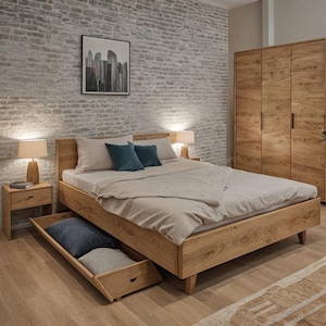 Può includere: Un letto in legno chiaro con comodino e armadio abbinati. Il letto ha un cassetto estraibile ed è realizzato in legno chiaro. Il letto è fatto con un piumino beige e cuscini. Due lampade sono sui comodini.