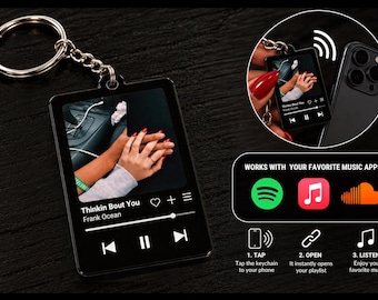May include: A rectangular black keychain featuring a music player interface with a photo of two hands holding, the song title Thinkin Bout You by Frank Ocean, playback controls, and icons for Spotify, Apple Music, and SoundCloud integration.