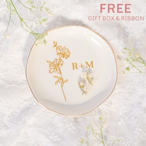 May include: A white ceramic ring dish with a gold floral design and the initials "R + M". Two pearl and crystal earrings rest on the dish. The words "FREE GIFT BOX & RIBBON" are in the top right corner.