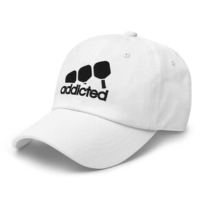 May include: White baseball cap with black embroidery of three paddleball paddles and the word "addicted".