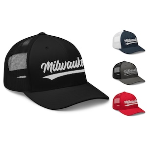 May include: Black, grey, red and navy blue trucker hats with a white embroidered "Milwaukee" logo. The hats have a mesh back and a curved brim.