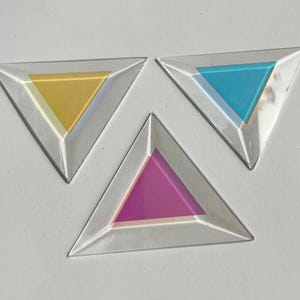 May include: Three triangular glass dishes with different colored glass inserts. The dishes are yellow, blue, and purple.