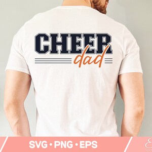 May include: White t-shirt with the text "CHEER dad" in black and orange lettering. The text is in a varsity style font.