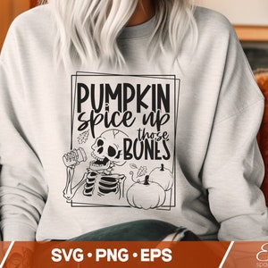 May include: A white sweatshirt with a black graphic design that says "Pumpkin spice up those bones". The graphic also features a skeleton holding a jar of pumpkin spice and two pumpkins.