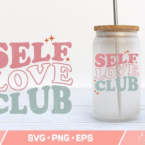May include: A clear glass tumbler with a wooden lid and a metal straw. The tumbler has the text "SELF LOVE CLUB" printed on it in pink and blue letters with orange stars.