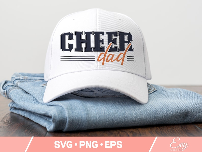 May include: White baseball cap with a navy blue "Cheer dad" graphic in a vintage style font. The text is outlined in black and has three black stripes underneath.
