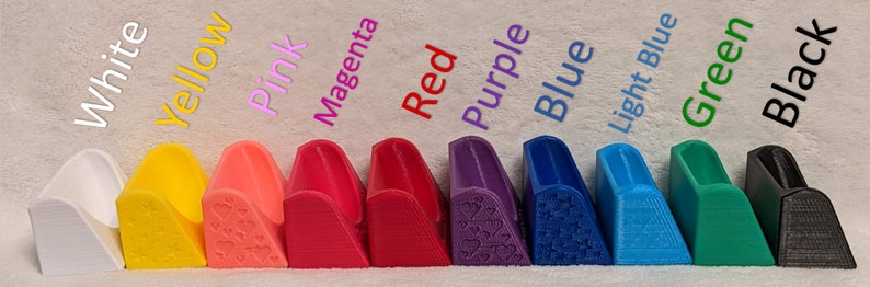 May include: A range of 3D-printed shoe heel protectors in colours such as white, yellow, pink, magenta, red, purple, blue, light blue, green, and black. Each protector has a unique design and is labelled with its colour.