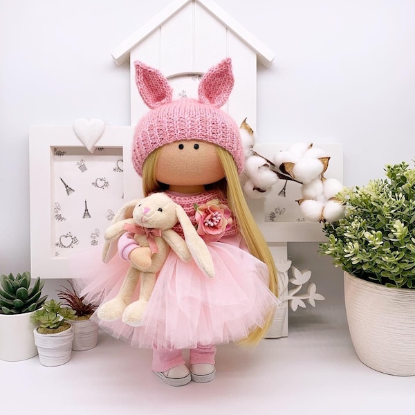 Interior fashionable textile doll Tilda, dressed in a pink fluffy tutu skirt, accompanied by a small bunny