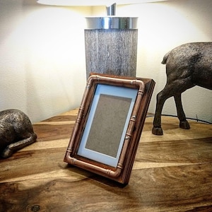 Puede incluir: Un marco de fotos de tubería de cobre con respaldo de madera. El marco está sobre una mesa de madera.