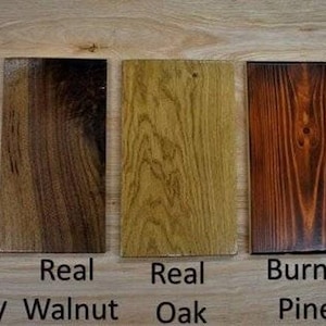 May include: Five wood samples, each labeled with the type of wood. The samples are arranged from left to right: Real Mahogany, Real Walnut, Real Oak, Burnt Pine, Burnt Oak.