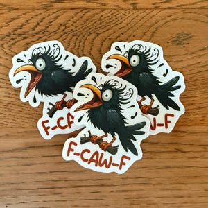May include: Three stickers featuring a cartoon crow with an open beak, perched on a branch. The crow is black with a yellow beak and is surrounded by musical notes. The text "F-CAW-F" is printed on the sticker.