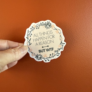 May include: A white sticker with a floral border and the text "All things happen for a reason but WTF" in black.